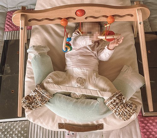 Säugling in Wippe mit Gips am Spielen
