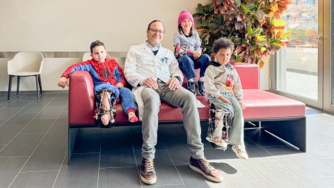 Dr. med. univ. Hannes Manner mit drei Kindern auf einem Sofa im Foyer