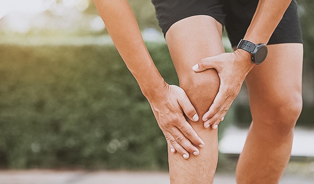 Mann fasst sich ans Knie