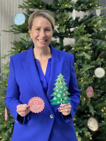 Frau in blauem Anzug vor Weihnachtsbaum